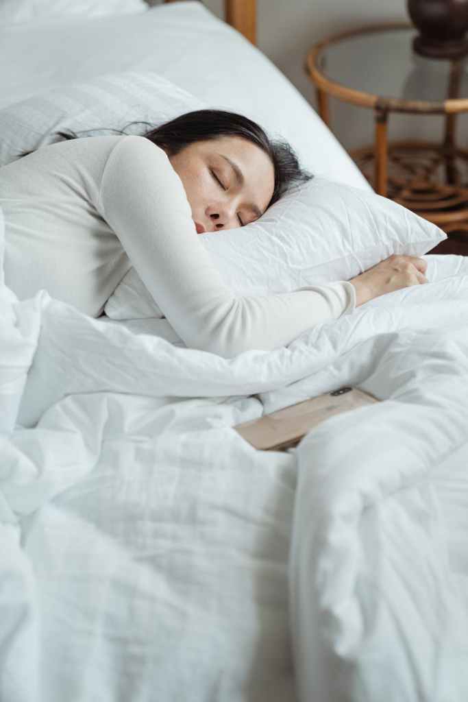 Manage perimenopause brain fog symptoms by prioritizing sleep. woman in white long sleeved shirt lying on bed