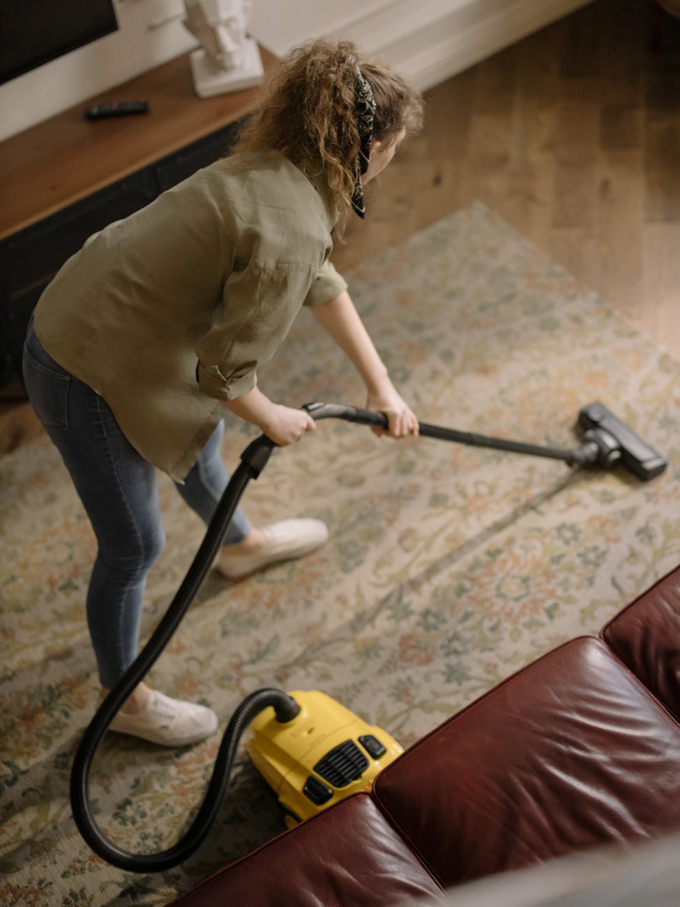 woman in long sleeve shirt holding a vacuum cleaner; easy spring cleaning tips for overwhelmed women